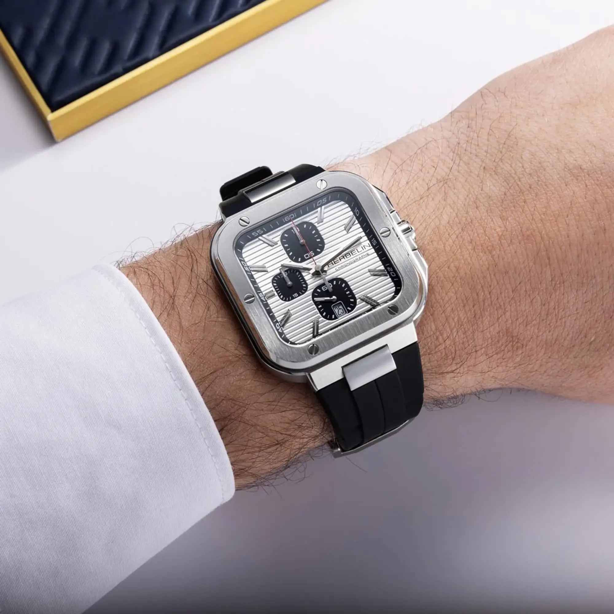 Au poignet masculin, cadran argent blanc et bracelet caoutchouc visibles