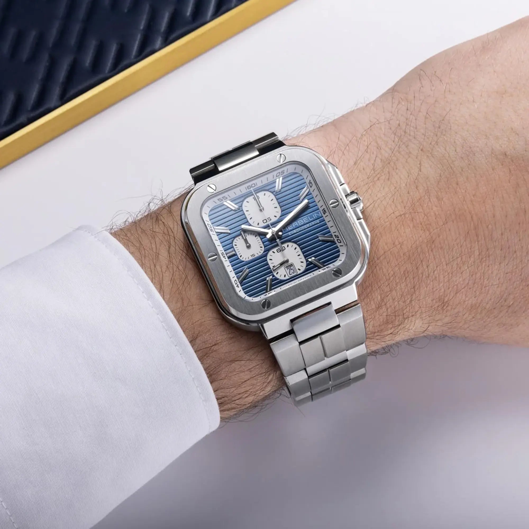 Au poignet masculin, cadran bleu et bracelet acier visibles