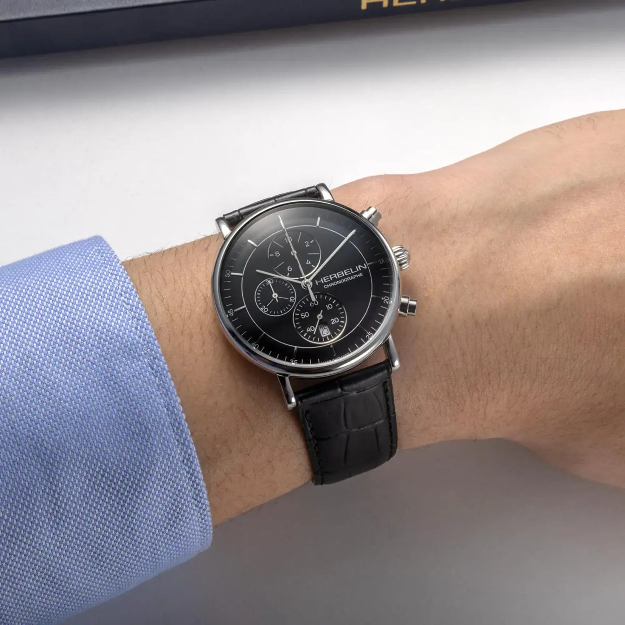 Au poignet masculin, cadran noir et bracelet cuir visibles