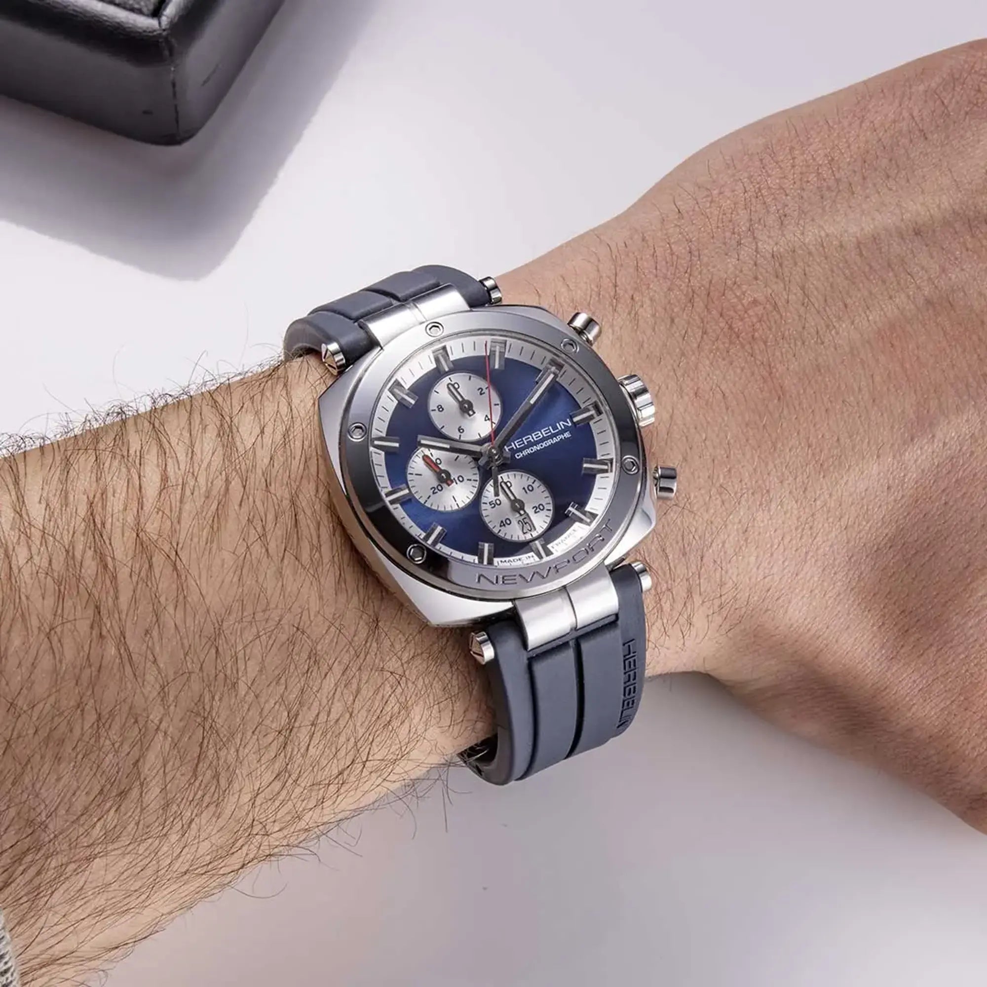 Au poignet masculin, cadran bleu et bracelet caoutchouc visibles