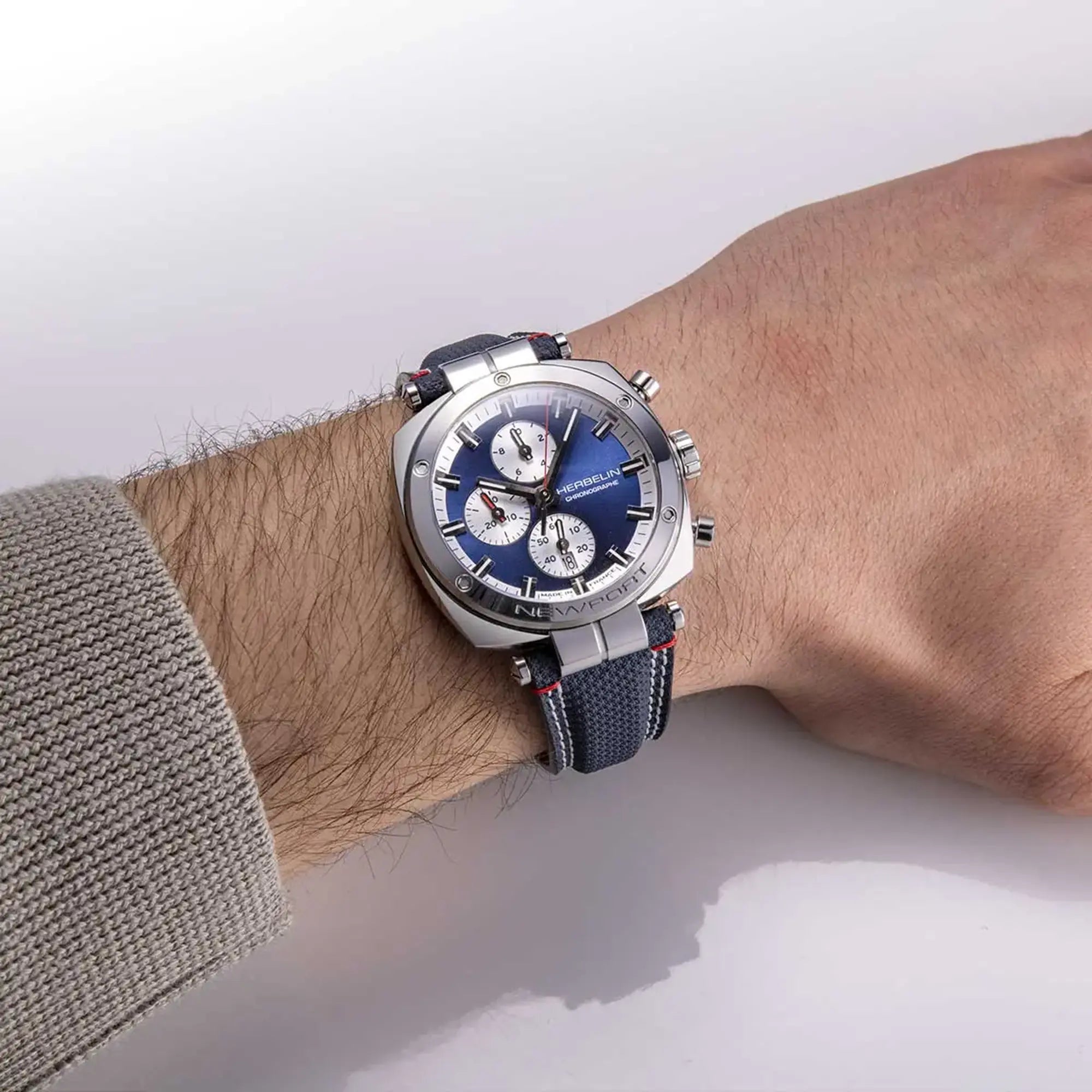 Au poignet masculin, cadran bleu et bracelet textile visibles