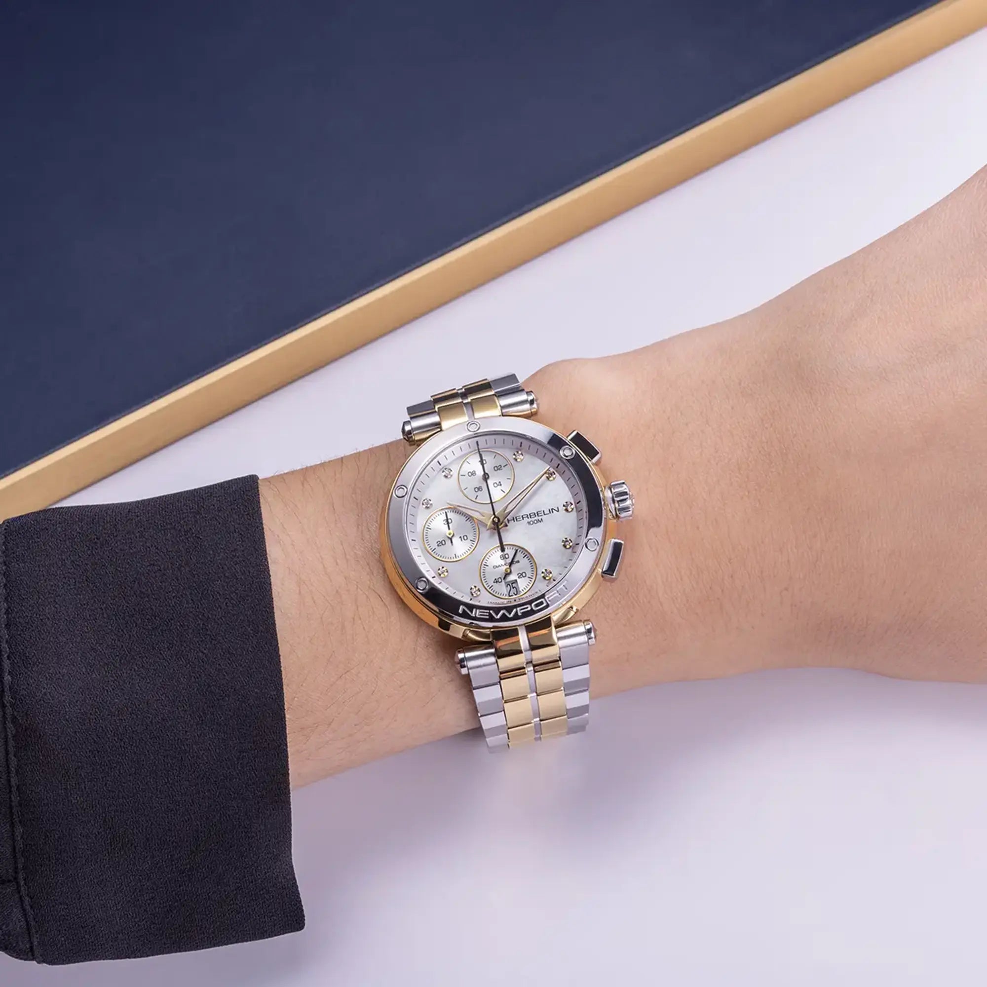 Au poignet féminin, cadran nacre blanche et bracelet acier bicolore visibles