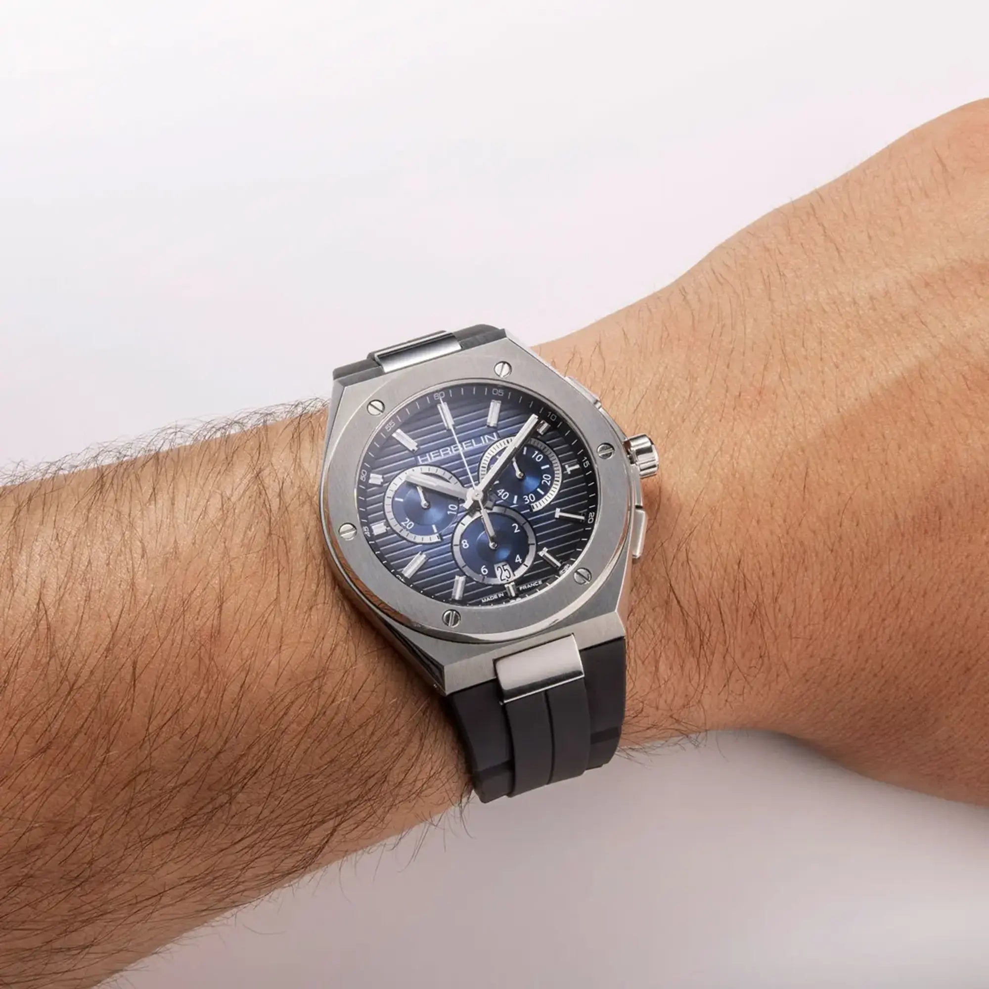 Au poignet masculin, cadran bleu dégradé et bracelet caoutchouc visibles