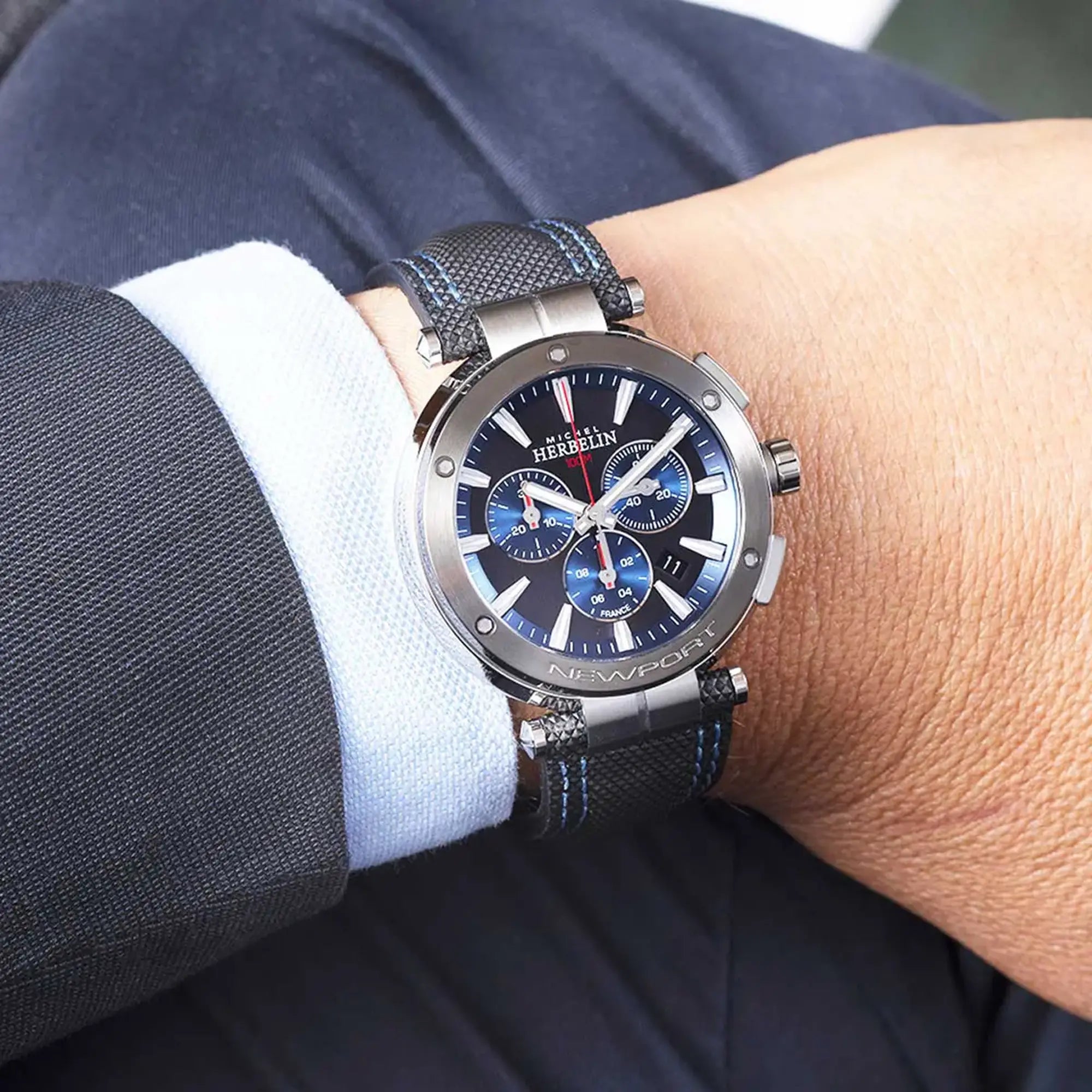 Au poignet masculin, cadran noir brossé et bracelet cuir visibles