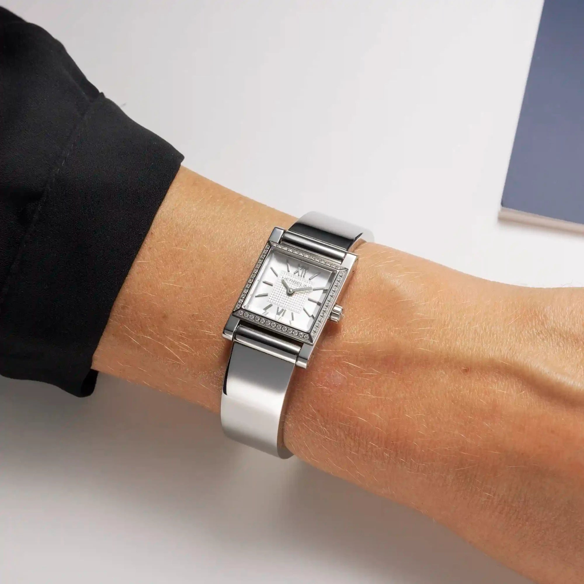 Au poignet féminin, bracelet bangle en acier avec boîtier Antarès serti