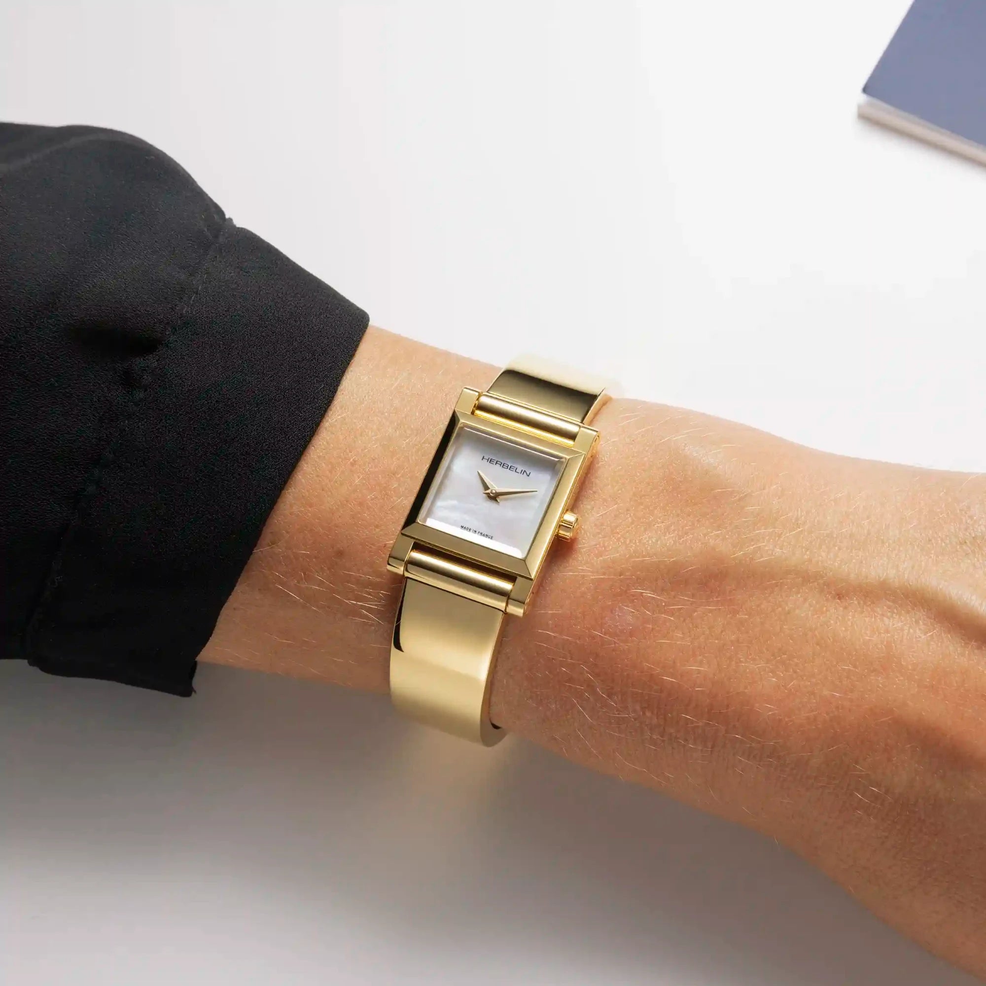 Au poignet féminin, bracelet bangle en acier PVD or avec boîtier Antarès