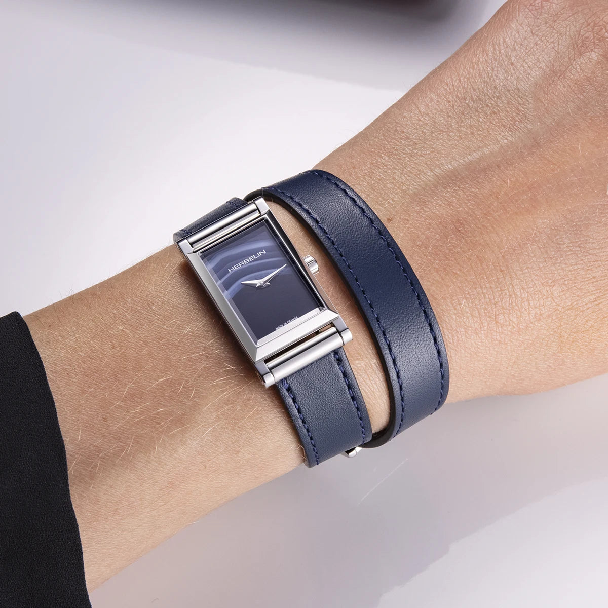 Au poignet féminin, cadran agate bleue et bracelet cuir bleu double tour visibles